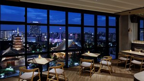 A modern restaurant with large windows offering a city view at night. - OMO3 Asakusa by Hoshino Resorts (Tokyo)