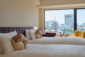 A hotel room with two beds, a view of a traditional pagoda, and a cityscape.