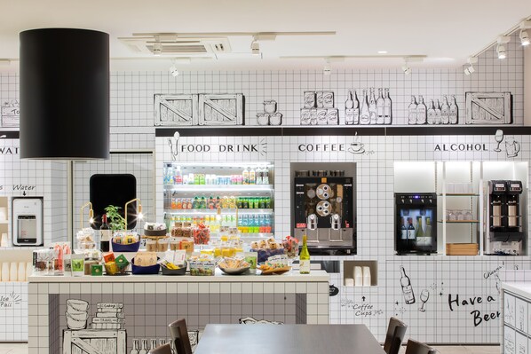 Una cafetería con una pared de azulejos, una máquina de café y una variedad de alimentos y bebidas exhibidos en la barra.
