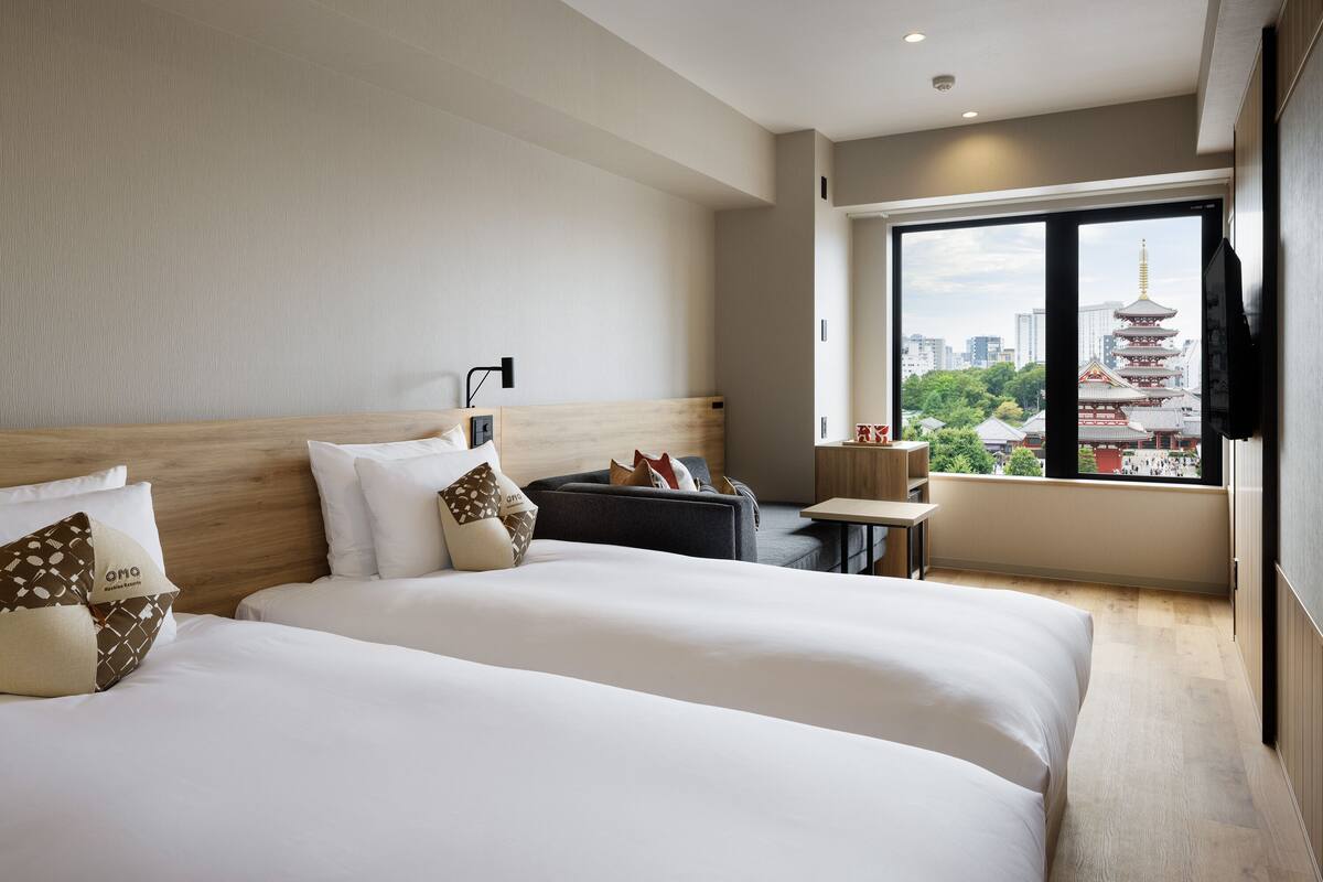 A hotel room with two beds, a small table, and a view of a traditional pagoda.