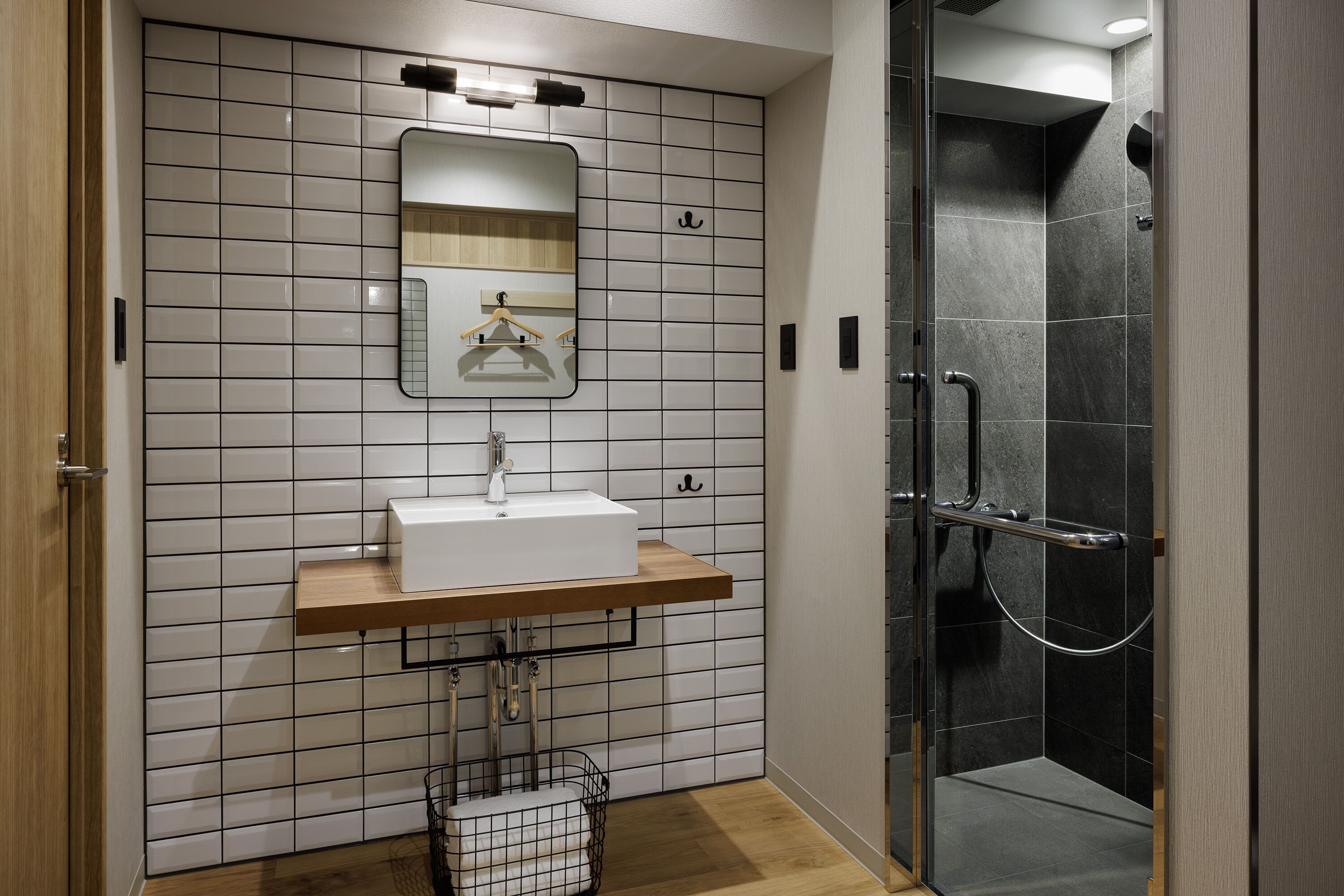Une salle de bain moderne avec un lavabo blanc, un miroir et une douche.