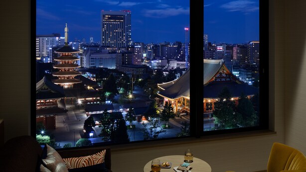 A room with a large window offering a view of a traditional pagoda and modern buildings at night. - OMO3 Asakusa by Hoshino Resorts (Tokyo)