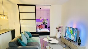 A modern living room with a grey sofa, a white coffee table, and a flat-screen TV. - Sublime atypical apartment Le Puits (Noisseville)