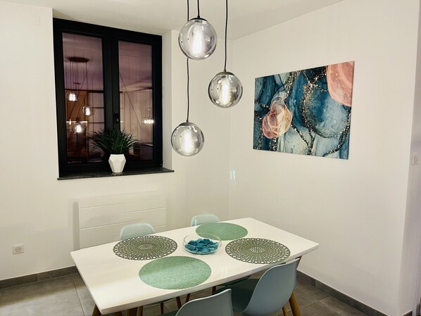 A dining area with a white table, green placemats, and a painting on the wall.