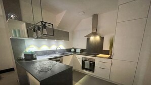 A modern kitchen with a central island, a stove, oven, and a sink. - Sublime atypical apartment Le Puits (Noisseville)