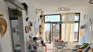 A well-lit, open-plan living space with a kitchenette, dining area, and a bed.