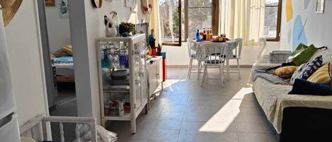 Un espacio habitable amplio y bien iluminado, con kitchenette, comedor y una cama.
