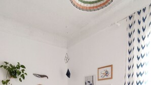 A bedroom with a bed, a hanging light fixture, a potted plant, and wall art.