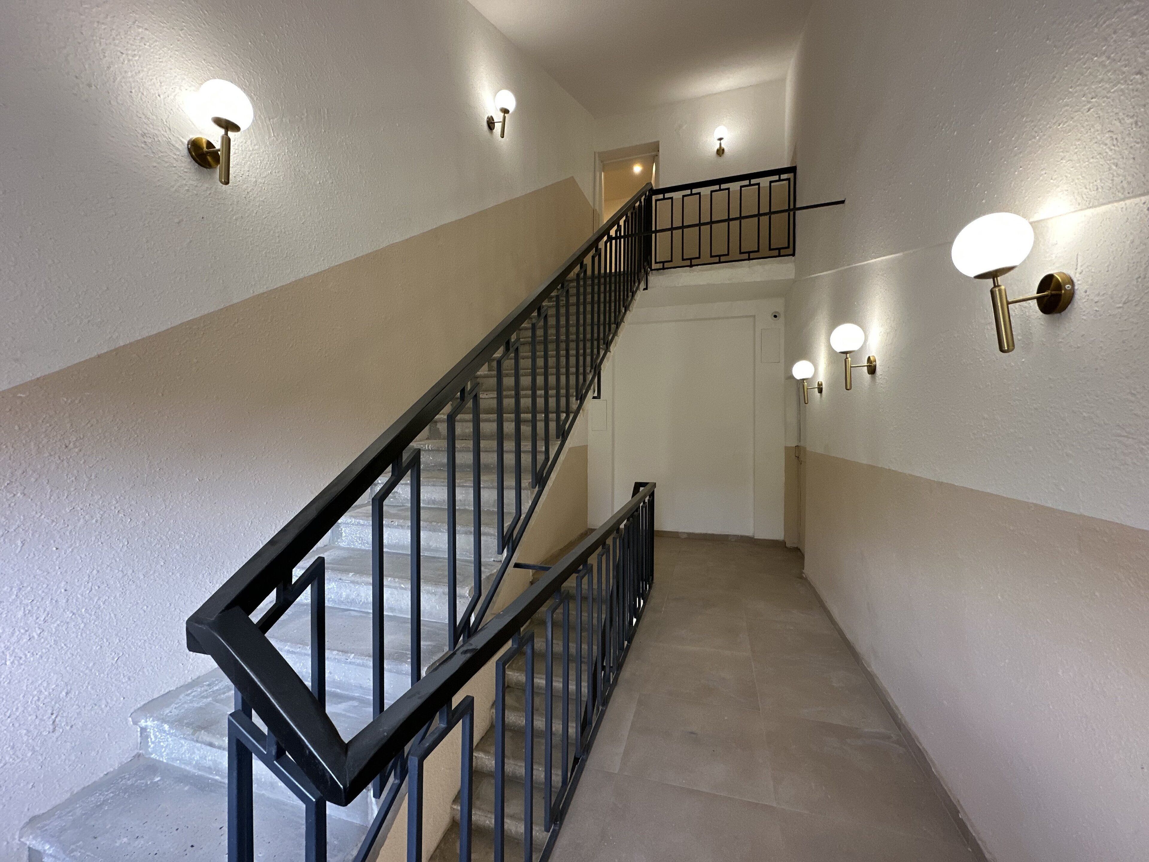 A staircase with black railings and wall-mounted lights.