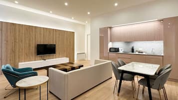 A modern living room with a sofa, a TV, and a dining area with a table and chairs.