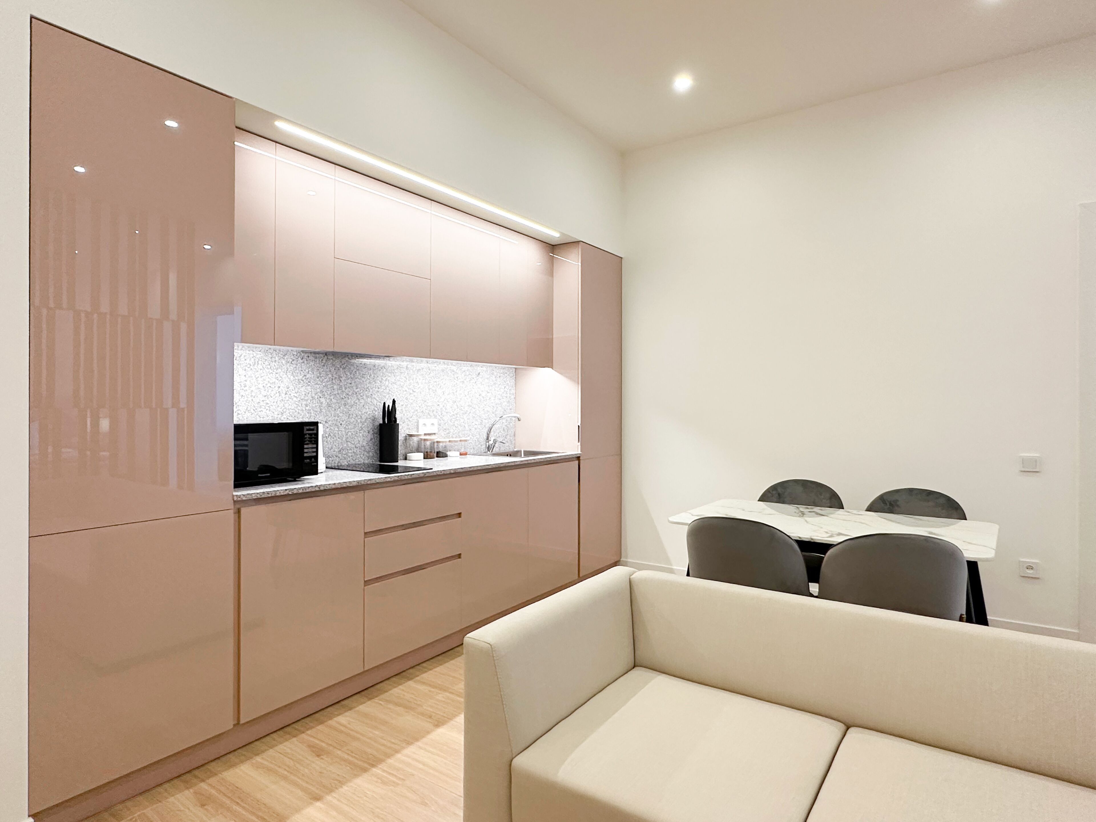 A modern kitchen with a microwave, sink, and cabinets. There is a dining area with a table and chairs.