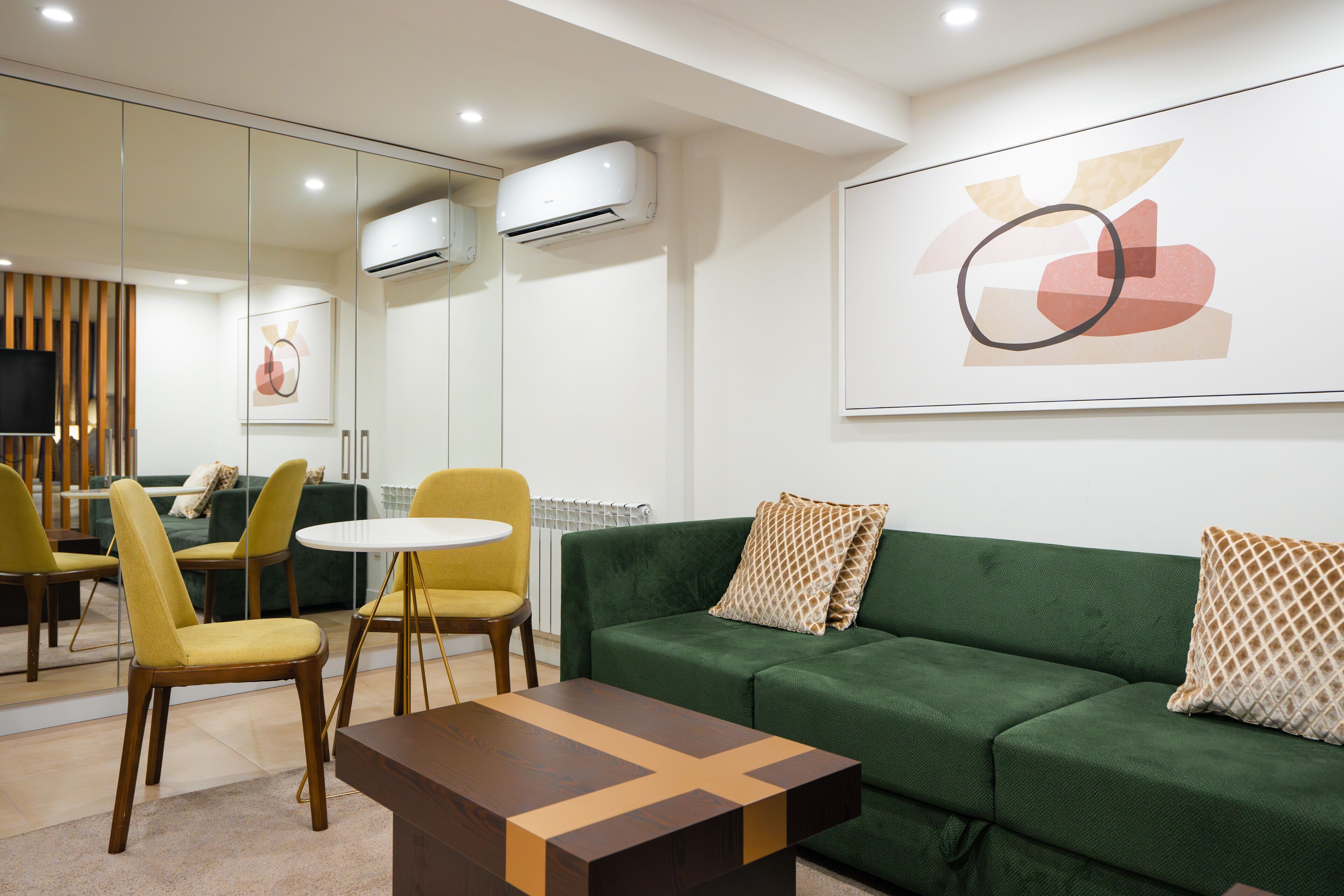 Una sala de estar moderna con un sofá verde, sillas amarillas, una mesa blanca y una mesita de centro.
