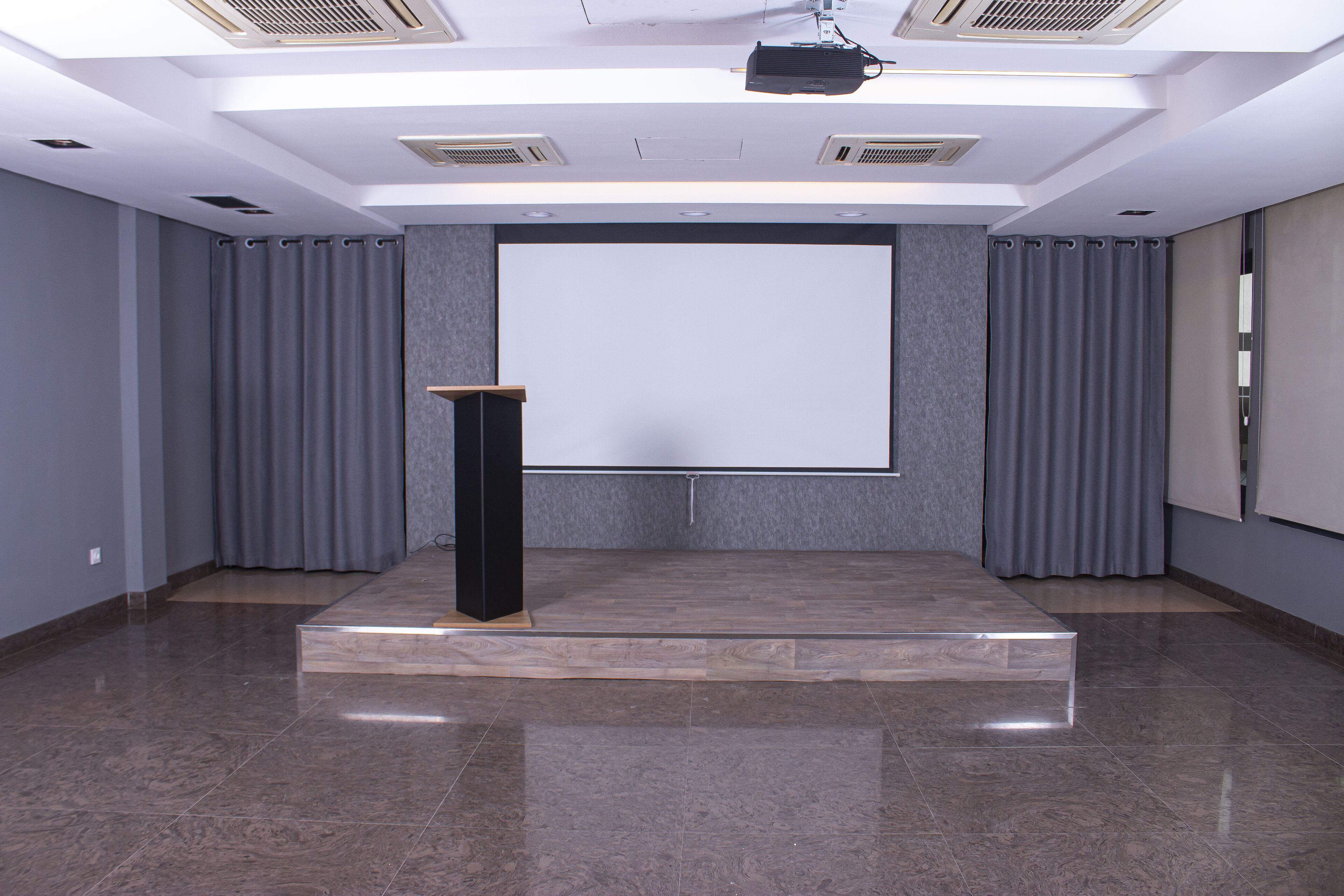 Una sala de conferències amb un escenari, una pantalla gran i cortines.