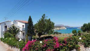 A coastal property with a white building, a view of the sea, and a stone wall with pink flowers. - Cost Mari Boutique Hotel  (Apokoronas)