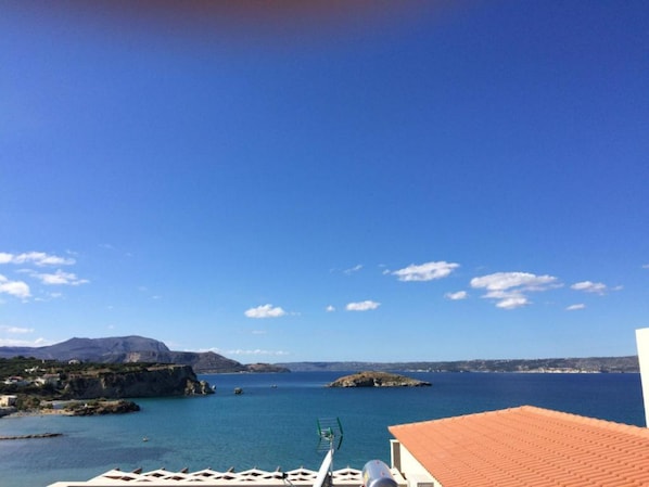 Vista costera con cielo despejado, una montaña al fondo y una masa de agua.