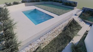 A modern outdoor pool area with a rectangular pool, surrounded by stone walls and lush greenery. - Cost Mari Boutique Hotel  (Apokoronas)