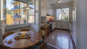 A compact kitchen with a dining area, large windows, and a view of neighboring buildings. - In the Heart of Santa Margherita by Wonderful Italy (Santa Margherita Ligure)