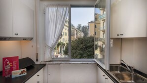 A small kitchen with a window view of buildings and trees. - In the Heart of Santa Margherita by Wonderful Italy (Santa Margherita Ligure)
