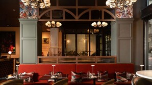 A restaurant with red booths, wooden tables, and chandeliers. - The Address Glasgow (Glasgow)