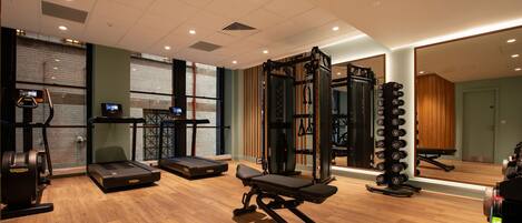 Un gimnasio con cintas de correr, máquinas de pesas y una estructura para sentadillas.