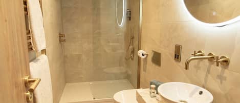 A modern bathroom with a glass-enclosed shower, a white sink, and a toilet.