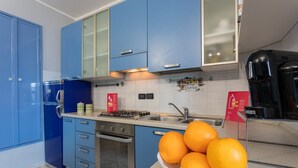 Une cuisine avec des meubles de rangement bleus, une cuisinière à gaz, un évier et un saladier rempli d’oranges.