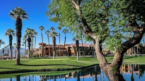 A resort with a pool, palm trees, and a building with a red roof.
