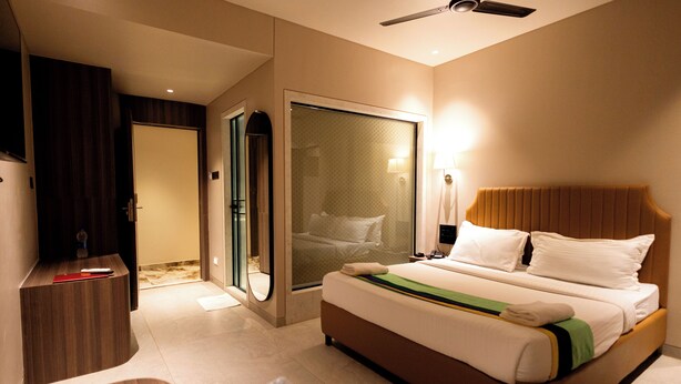 A hotel room with a bed, a desk, a mirror, and a door leading to a bathroom. - HOTEL GOLDEN TULIPZ (Mumbai)