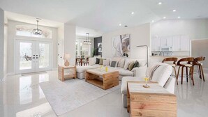 Amplia sala de estar con sofá blanco, mesa de centro de madera y comedor con sillas.