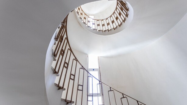 Un escalier en colimaçon avec un intérieur blanc et des rampes en bois.