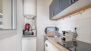 A compact kitchen with a washing machine, a coffee maker, and a toaster.