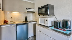 A compact kitchen with a dishwasher, a microwave, and a toaster on a countertop.