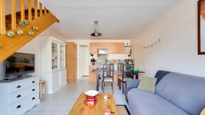Een moderne woonkamer met een houten trap, een eethoek en een keuken op de achtergrond.