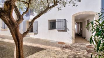 Un bâtiment à l’extérieur blanc, un arbre au premier plan et un chemin de gravier.
