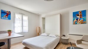 A modern hotel room with a bed, a small table, a chair, a sofa, and artwork on the walls. - 150m from St Martin de Ré harbour, studio for 2 (Saint-Martin-de-Ré)