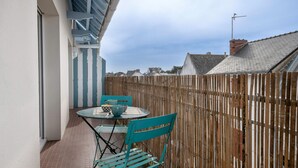Uma varanda com mesa e cadeiras, uma cerca de madeira e vista para casas vizinhas.