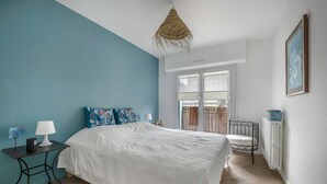 Quarto com uma cama, mesa de cabeceira, abajur, janela e radiador.
