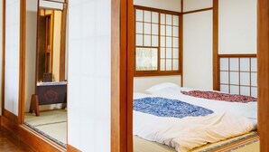 Ein traditioneller japanischer Raum mit Tatami-Boden, einem niedrigen hölzernen Bett, schiebbaren Shoji-Türen und einer Deckenleuchte.