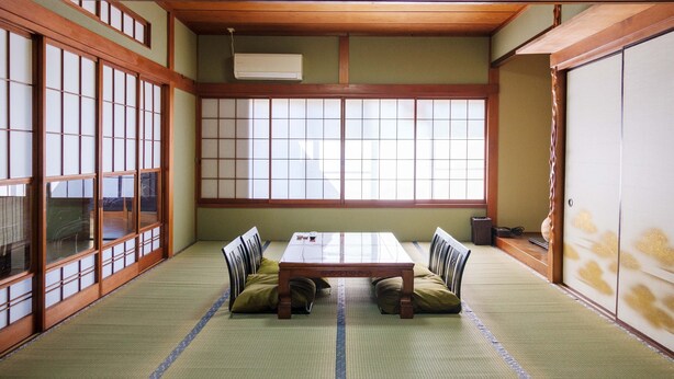 Ein traditioneller japanischer Raum mit Tatami-Böden, einem niedrigen Holztisch und Shoji-Schirmwänden.