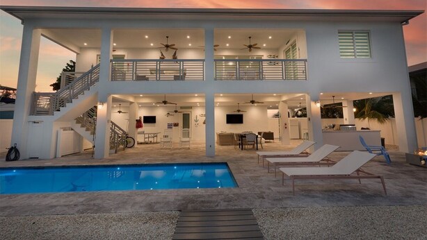 A two-story house with a swimming pool, outdoor seating, and a balcony.