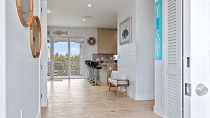A modern interior with a wooden floor, a kitchen area, and a balcony with a view.