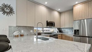 A modern kitchen with a granite countertop, stainless steel appliances, and wooden cabinets.