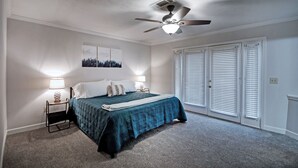 A bedroom with a bed, nightstands, a ceiling fan, and a window with blinds.