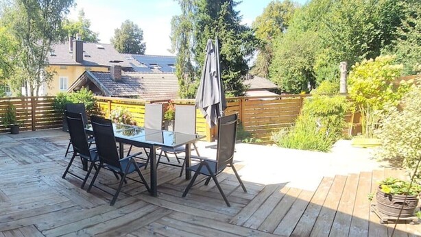 A wooden deck with a glass table and chairs, surrounded by a wooden fence and greenery. - Sigrid's vacation apartment Bad Tölz (Bad Tölz)