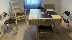 Ein Essbereich mit einem Tisch für vier Personen, einer Wanduhr und einem Fenster mit blauen Vorhängen.