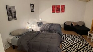 Ein Schlafzimmer mit zwei Betten, einem gemusterten Teppich und Wandbildern.
