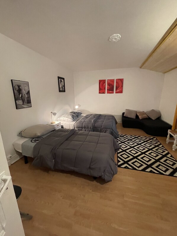 A bedroom with two beds, a patterned rug, and wall art.