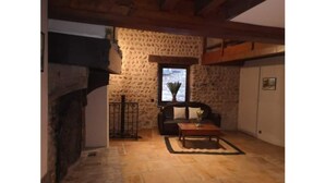 Une pièce aux murs de pierre, dotée d’une cheminée, d’un canapé et d’une table basse.