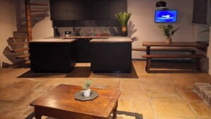Une cuisine moderne dotée d’un îlot central, de meubles de rangement aux couleurs sombres et d’un téléviseur à écran plat fixé au-dessus de l’îlot.