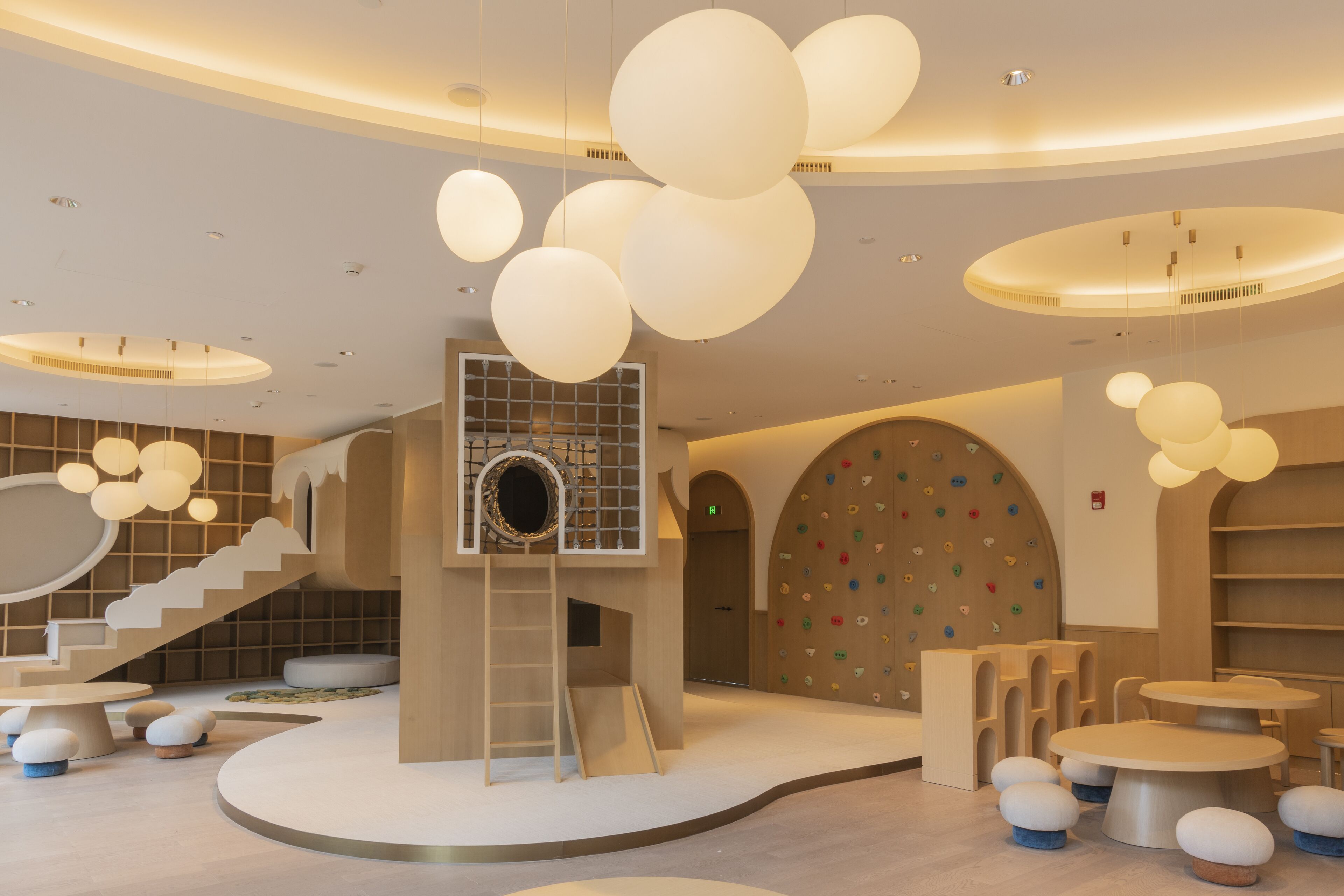 Un espace intérieur moderne doté d’un escalier central, de coins salons circulaires et d’un mur d’escalade.